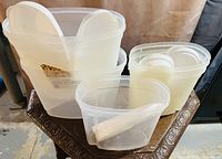 Five translucent white plastic storage containers with matching lids, arranged on a table against a neutral background.