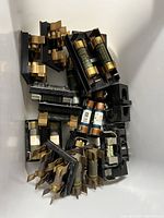 Multiple assorted electrical fuses and their holders arranged together showing different fuse types.