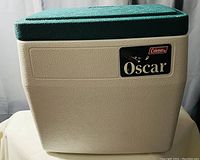 Front side of the Coleman Oscar cooler showing green lid and beige body with label.