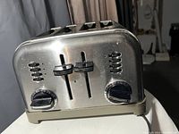 Stainless steel Cuisinart four slice toaster showing front control panel with knobs and sliders for toasting settings.
