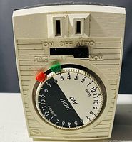 Front view of heavy duty 24 hour appliance timer showing dial with day and night markings, manual override switches, and two outlet slots.
