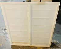 White plastic Ikea underbed storage bin with two hinged lids, viewed from above, showing the full shape and lid design.