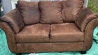 Front view of camel-colored microfiber loveseat sofa showing two seat cushions and three back cushions with cushioned armrests.