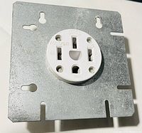 Close-up view of a white ceramic oven plug attached to a galvanized metal mounting plate.