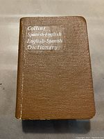 Front cover of the Collins Spanish-English English-Spanish pocket dictionary showing the brown textured cover and silver lettering.