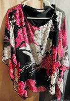 Front view of floral patterned blouse with pink and white flowers on black background.