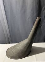 Front side view showing the funnel standing upright on its narrow spout end on a white surface with a grey backdrop.