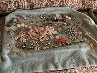 Wide view of various costume jewelry pieces spread on a towel, showing pins, brooches, and pearl necklaces.