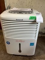 Front view of white Honeywell dehumidifier showing horizontal air vents, brand name, water level indicator, and green size label.