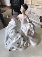 Angled front-left view showing the figurine's face, dress details, and rose in hand.