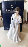 Front view of Royal Doulton figurine with original box behind it, showcasing the figurine's detailing and condition.