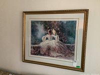 Framed print showing woman in historical dress holding a fan seated next to a stone wall with flowers in the background.