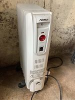Front view of white NOMA oil filled heater showing control panel with red dial and power switch.