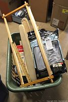 Plastic tub containing wooden sewing frame, sleeve ironing board frame, ironing board cover, and other items.