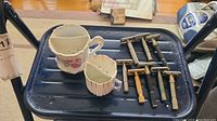 Photo of two vintage ceramic shaving mugs and nine vintage double-edge safety razors arranged on a tray