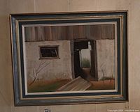 Framed painting showing a rustic barn exterior with an open door and small window. Earth tone color palette with bare tree branches in the foreground.