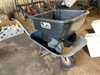 Side view of blue metal wheelbarrow with black plastic yard cart inside