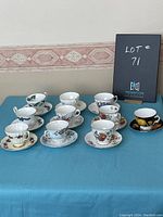 Front view showing all cups and saucers arranged with varied floral and bird patterns