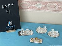 Overall view of five sets of crystal animal figurines on mirrored bases displayed on blue cloth, including clear and gold-colored crystals.
