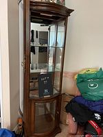 Electrohome wooden curio cabinet with closed glass door showing mirrored back and two glass shelves, measuring 69.5 x 20 x 13 inches.