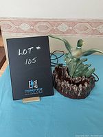Duck table lamp showing front and power cord on blue surface with lot signage.