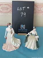 Both Royal Doulton and Coalport figurines side by side with lot number sign in background