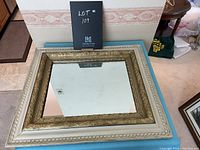 Front view of the vintage double-framed mirror showing the gold inner frame and off-white outer frame with decorative details.