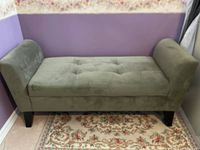 Bench shown from side angle with tufted seat and curved arms in khaki green upholstery.