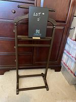 Front view of wooden men's valet stand showing height and horizontal bars for hanging.