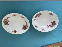 Two oval vintage Royal Albert serving bowls with floral design and scalloped edges on a blue background.