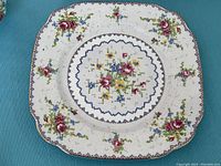 Close-up photo of a luncheon plate showing petit point floral pattern with gold trim on white porcelain.