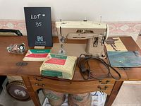 Singer sewing machine with accessories including user guide and bobbins laid out on wooden table.