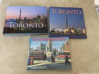 Photo showing three coffee table books about Toronto, including 'Toronto Then & Now', 'Toronto', and 'Not A One Horse Town' by Mike Filey.