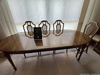 Front view of walnut dining table with three matching chairs and two table leaves inserted