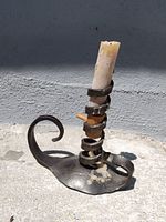 Metal candle holder with spiral wrap and used candle, wax residue visible on base