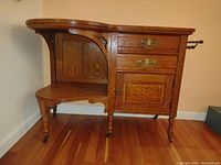 Front view showing serpentine top, two drawers above cabinet door, under-shelf, turned legs and towel rack.