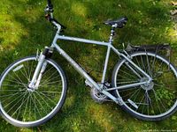 Side view of the full hybrid bicycle showing silver frame, wheels, handlebar and saddle.