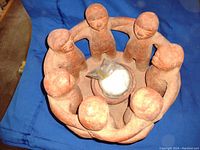 Photo showing top and side views of the circular clay candle holder featuring 7 standing figures that hold hands forming a ring around a central bowl.