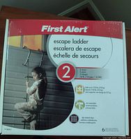 Photo of First Alert escape ladder box showing branding, a child descending the ladder, and product features.