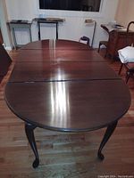 Full view of the large oval dining table with two leaf extensions in place, showing the satin finish top and the cherry wood surface.