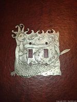 Front view of metal light switch plate with mermaid design, showing artistic details and two switch openings.