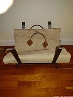 Vintage LL Bean canvas and leather handled firewood carrier mounted on the cast iron rack.