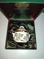 Miniature porcelain box with floral and bird pattern inside green silk-lined presentation box