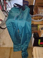 Teal blue waterproof racing bottoms size Medium laid out on floor, showing nylon/taffeta material and waterproof design