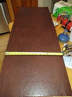 Four burgundy oval table pads laid out on a table with measuring tape showing length approx 41 inches.