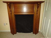 Front view of vintage wooden false front fireplace mantle showing the overall design, side columns, and corbels supporting the mantle shelf.