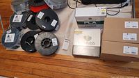 Overall lot showing multiple reels of 3D printing filament and boxes on wooden floor
