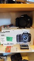 Camera body on top of original EOS 60D box with sealed battery pack and strap packaging