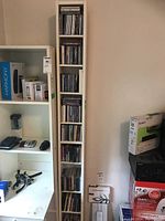 Tall narrow white shelving unit filled with CDs