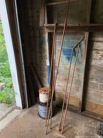 Bundle of copper pipes leaned against wooden wall beside wiring spools
